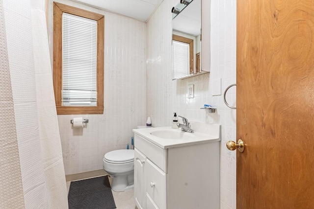 full bathroom with tile walls, toilet, vanity, tile patterned flooring, and plenty of natural light