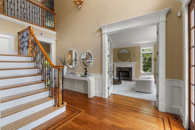 22 Scotney, Newton, MA 02467 - foyer entrance featuring wood finished floors, wainscoting, a premium fireplace, stairway, and a decorative wall