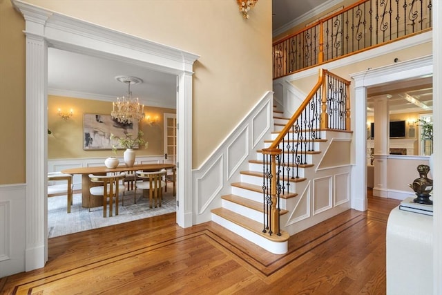 22 Scotney, Newton, MA 02467 - staircase featuring a decorative wall, wood finished floors, a chandelier, crown molding, and a wainscoted wall