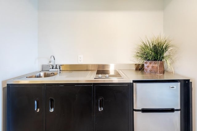 bar area with freestanding refrigerator, black electric cooktop, and a sink