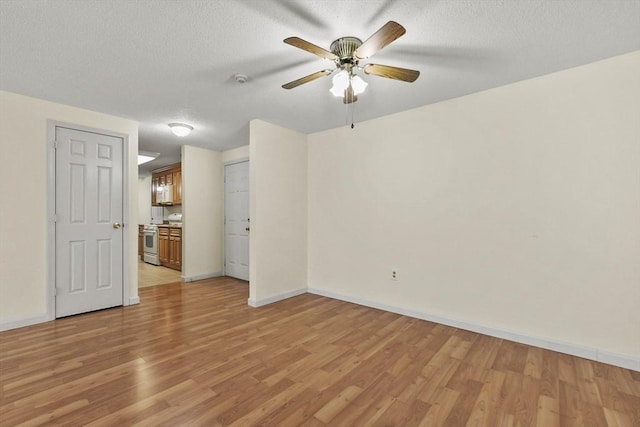 empty room featuring light wood-style floors, a ceiling fan, baseboards, and a textured ceiling