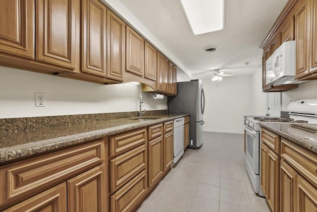 kitchen featuring white appliances, a ceiling fan, brown cabinets, a sink, and light tile patterned flooring