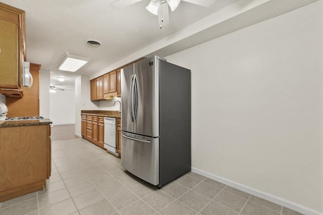 kitchen with white appliances, brown cabinetry, light tile patterned flooring, and a ceiling fan