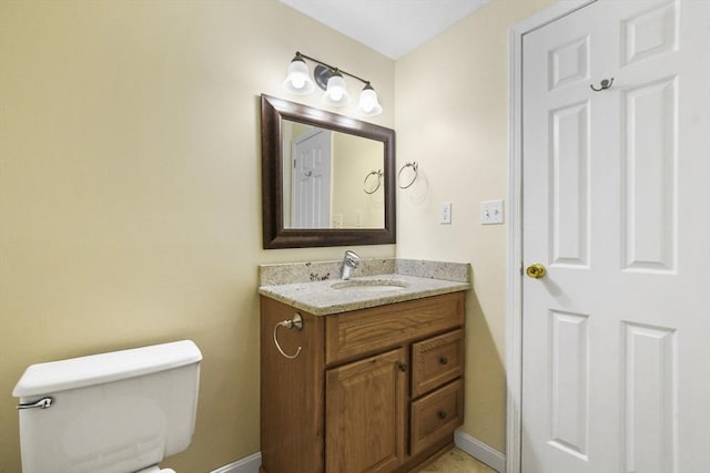 half bathroom featuring toilet, vanity, and baseboards