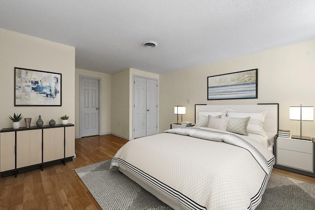 bedroom featuring a closet, visible vents, baseboards, and wood finished floors