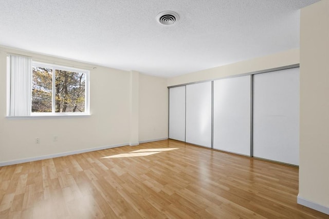 unfurnished bedroom with light wood-style floors, visible vents, and a textured ceiling