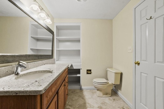 bathroom with toilet, vanity, and baseboards