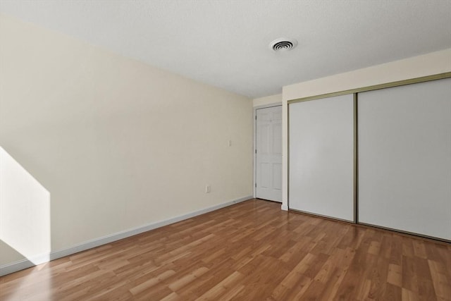 unfurnished bedroom with light wood-style floors, a closet, visible vents, and baseboards