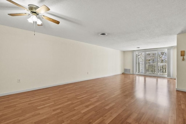 unfurnished living room featuring light wood finished floors, visible vents, a ceiling fan, a textured ceiling, and baseboards