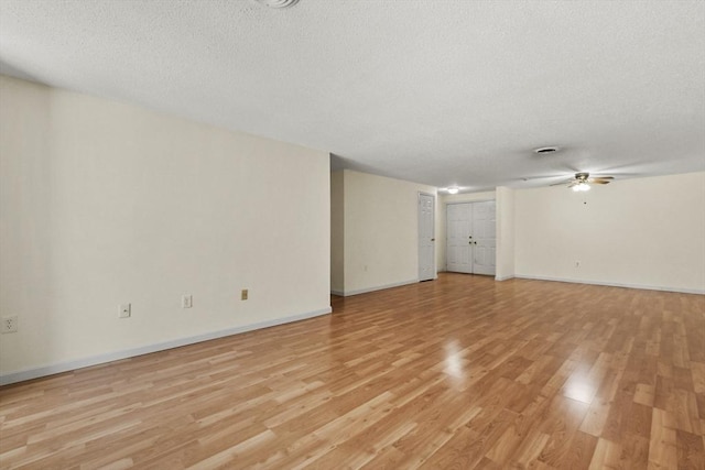 unfurnished room with a ceiling fan, baseboards, a textured ceiling, and light wood finished floors