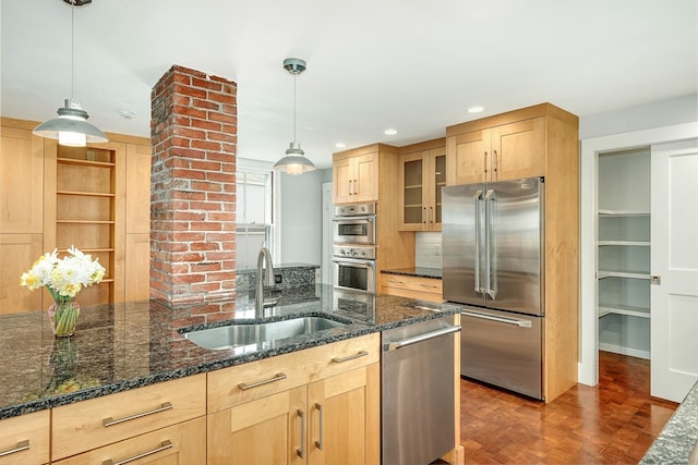 kitchen featuring decorative light fixtures, sink, appliances with stainless steel finishes, and dark stone counters