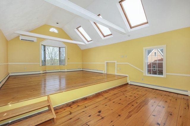 empty room with vaulted ceiling with skylight, a baseboard radiator, and a wealth of natural light