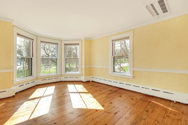 unfurnished room with light hardwood / wood-style flooring, crown molding, baseboard heating, and plenty of natural light