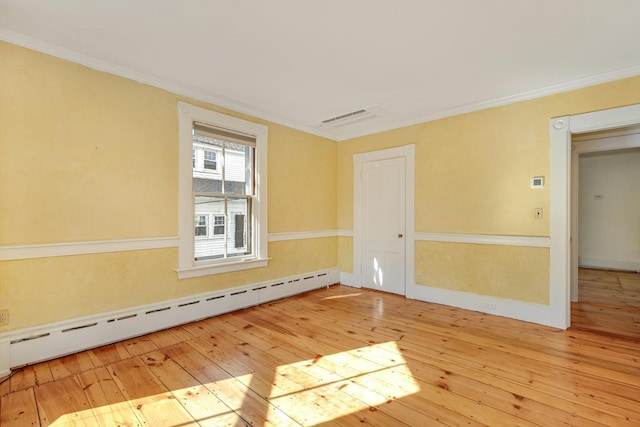 spare room featuring ornamental molding, light hardwood / wood-style floors, and a baseboard heating unit