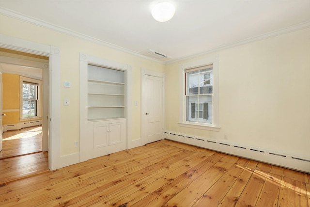 unfurnished room with light hardwood / wood-style floors, crown molding, baseboard heating, and built in shelves