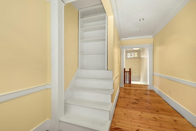 staircase with light hardwood / wood-style flooring and crown molding