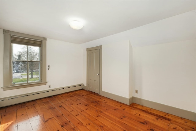 unfurnished room featuring hardwood / wood-style flooring and baseboard heating