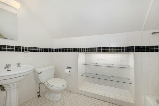 bathroom featuring tile flooring, vaulted ceiling, tile walls, and toilet