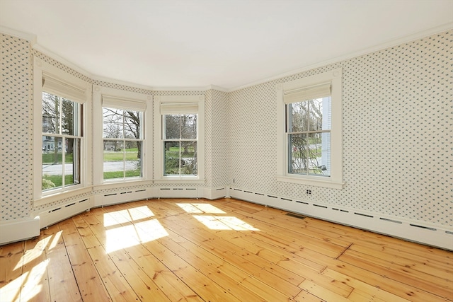 spare room featuring ornamental molding, light hardwood / wood-style floors, and a baseboard radiator