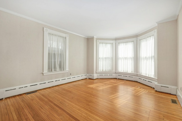 spare room with ornamental molding, a baseboard heating unit, and light hardwood / wood-style floors