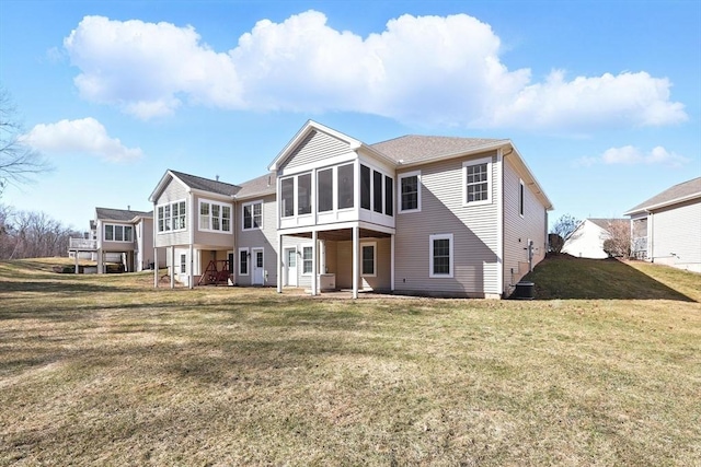 back of property with a lawn, central AC unit, and a sunroom