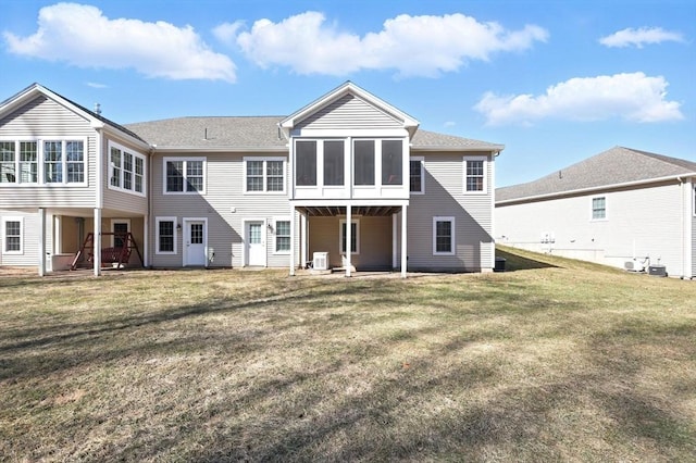 rear view of house with central air condition unit, a yard, and a sunroom