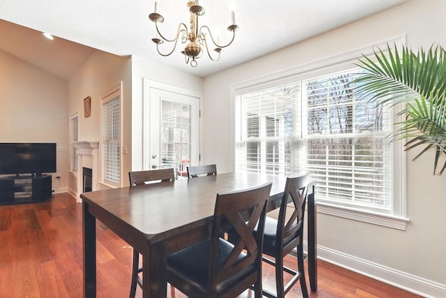 dining space with a wealth of natural light, baseboards, a notable chandelier, and wood finished floors