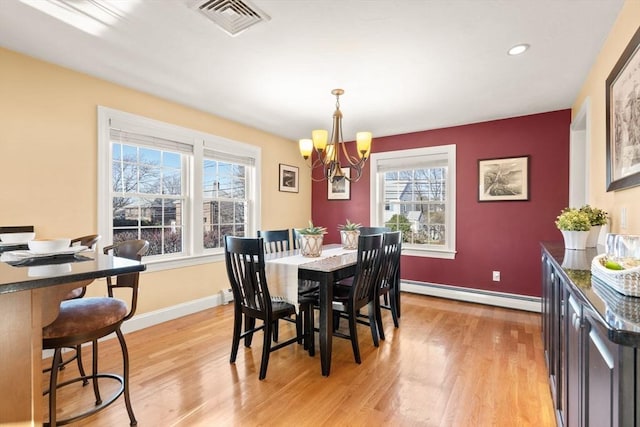 dining area featuring a baseboard heating unit, a wealth of natural light, a notable chandelier, and light hardwood / wood-style floors