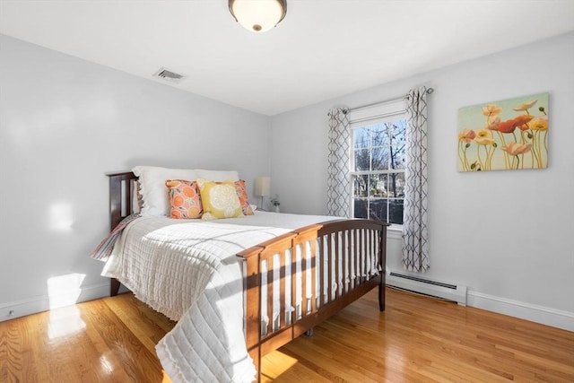 bedroom with a baseboard radiator and light wood-type flooring