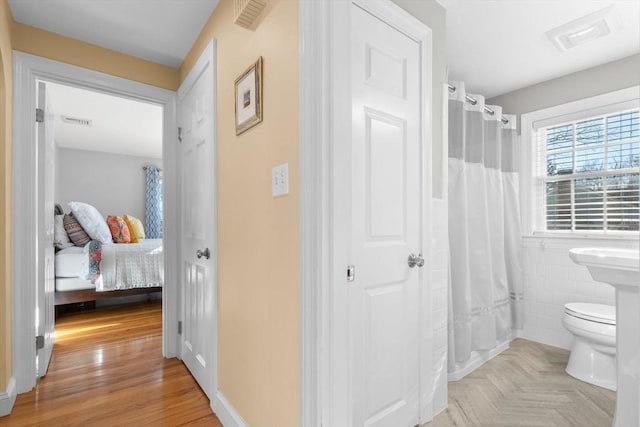 bathroom with tile walls, curtained shower, parquet flooring, and toilet