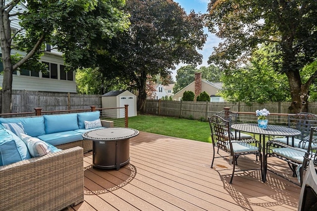 wooden deck with an outdoor hangout area, a lawn, and a shed