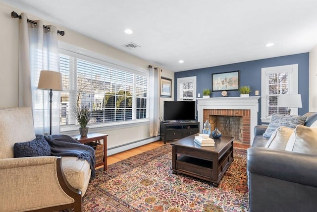 living room featuring a baseboard heating unit, hardwood / wood-style flooring, and a brick fireplace