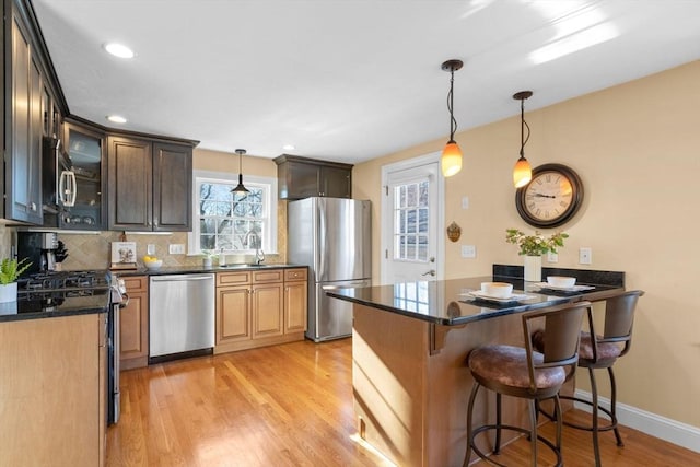 kitchen with sink, appliances with stainless steel finishes, tasteful backsplash, light hardwood / wood-style floors, and kitchen peninsula