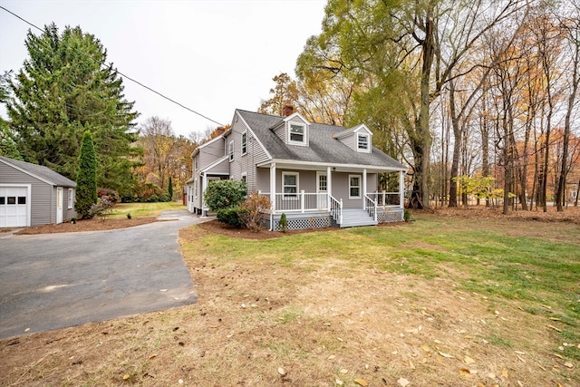 new england style home featuring a porch, a front lawn, and an outbuilding