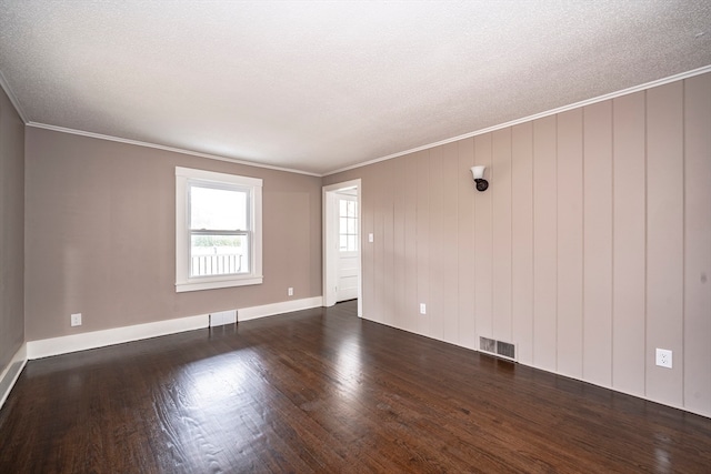 empty room with crown molding, a textured ceiling, wooden walls, and dark hardwood / wood-style flooring