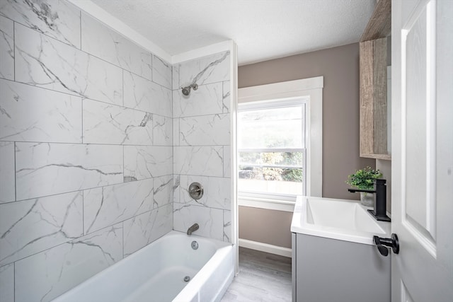 bathroom featuring vanity, tiled shower / bath combo, a textured ceiling, and wood-type flooring