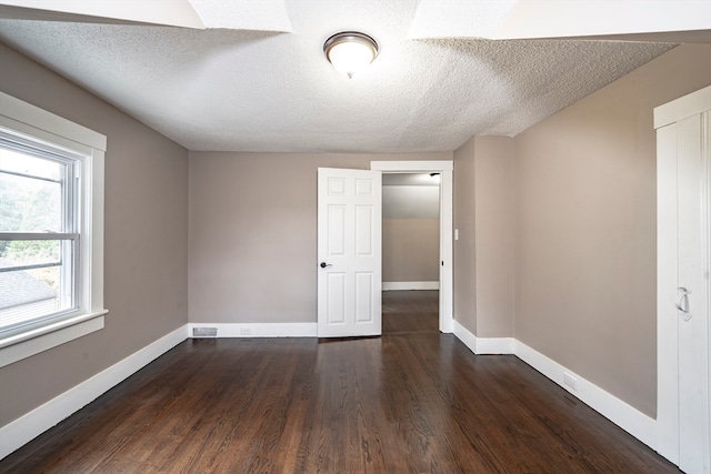 empty room with dark hardwood / wood-style floors and a textured ceiling