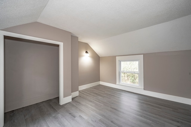 bonus room featuring hardwood / wood-style flooring, a textured ceiling, and vaulted ceiling