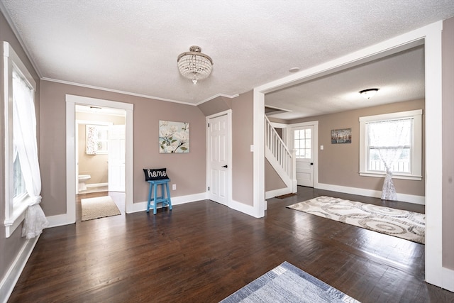 entrance foyer with a textured ceiling, dark hardwood / wood-style flooring, and ornamental molding