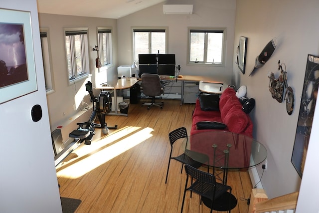 office space with a wall mounted AC, lofted ceiling, and hardwood / wood-style flooring