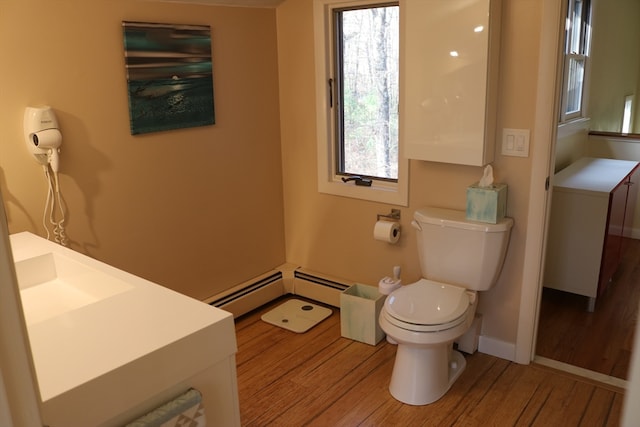 bathroom featuring toilet, vanity, wood-type flooring, and a baseboard heating unit