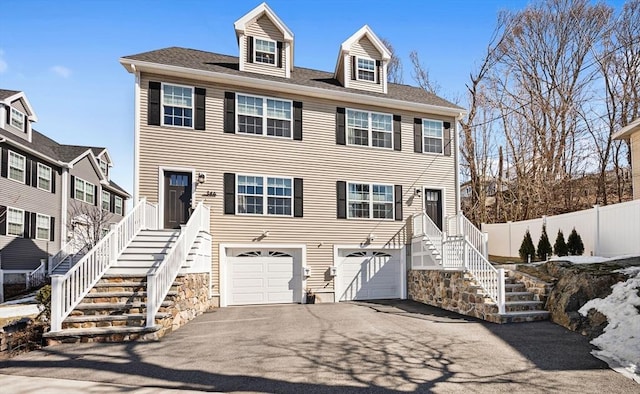 view of front of property featuring aphalt driveway, an attached garage, stairs, and fence