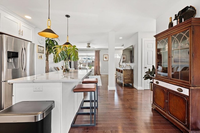 kitchen with a kitchen bar, pendant lighting, stainless steel refrigerator with ice dispenser, a kitchen island, and dark wood finished floors