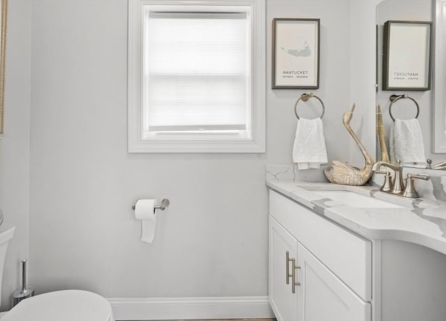 half bath with toilet, vanity, and baseboards