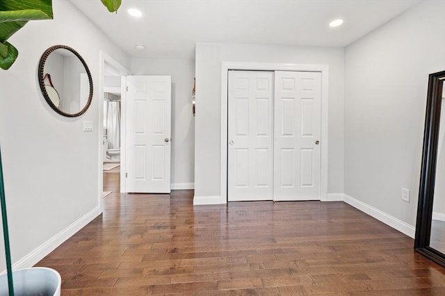 unfurnished bedroom featuring recessed lighting, wood finished floors, baseboards, and a closet