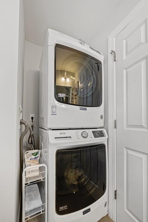 clothes washing area featuring stacked washer and dryer and laundry area