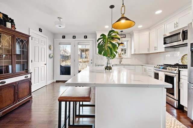 kitchen with a kitchen island, a breakfast bar, decorative backsplash, dark wood-style floors, and stainless steel appliances