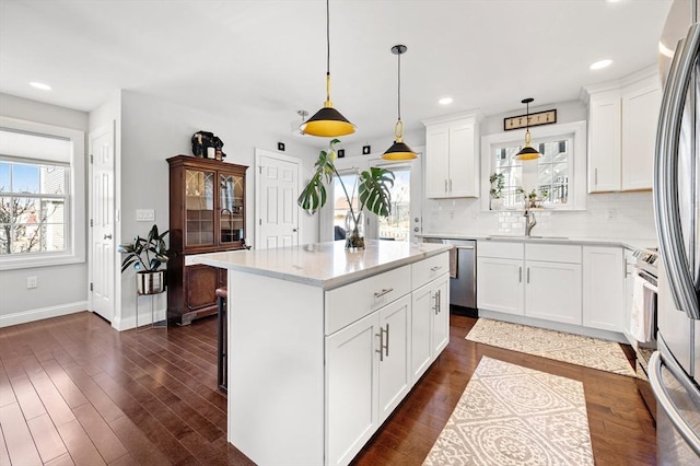 kitchen featuring a sink, backsplash, a center island, stainless steel appliances, and dark wood-style flooring