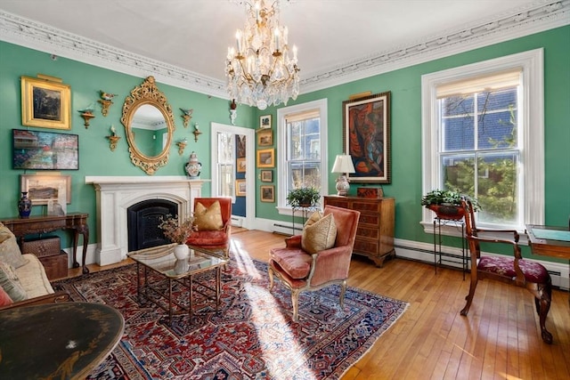 living area featuring a baseboard heating unit, hardwood / wood-style flooring, a fireplace, and ornamental molding