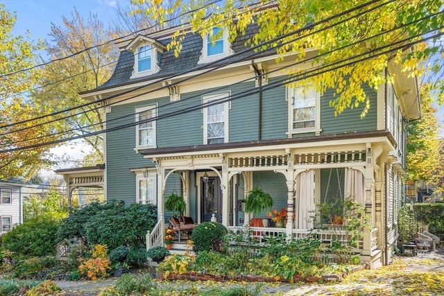 view of front of home featuring mansard roof and covered porch